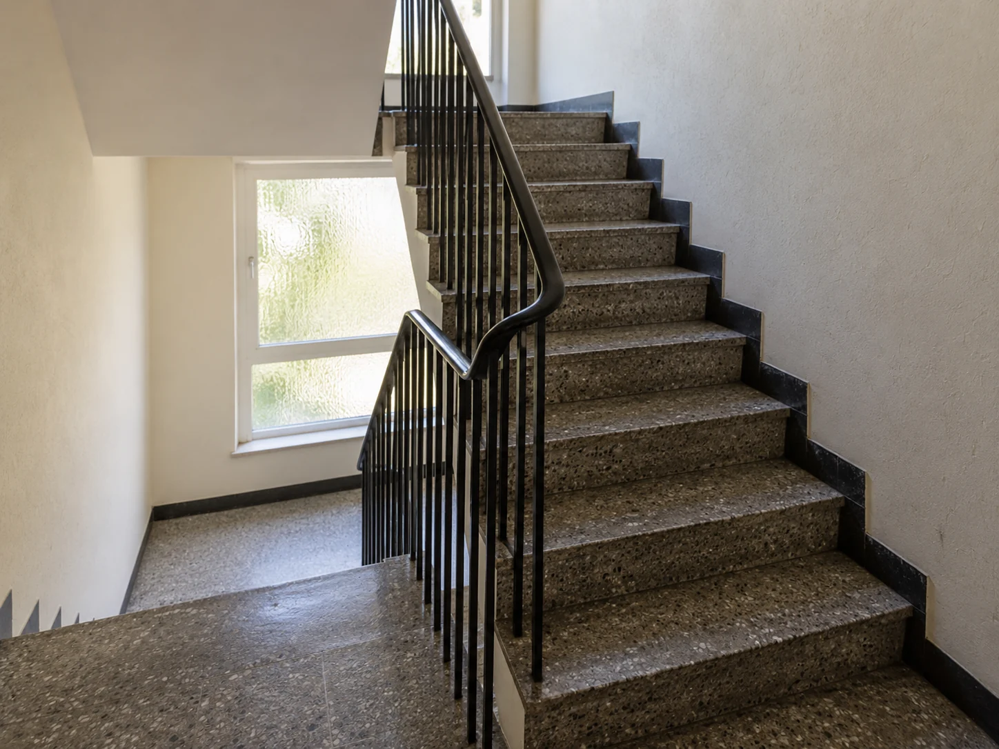 Fiktives Treppenhaus mit Terrazzo-Stufen und Tageslicht – KI-Illustration